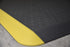 Corner shot of black Traxtion mat with yellow safety strip. 