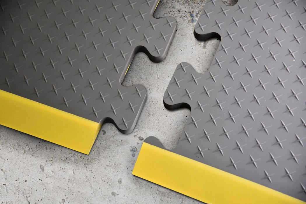 Up Close shot of puzzle piece edges of gray Traxtion mat with safety strip.